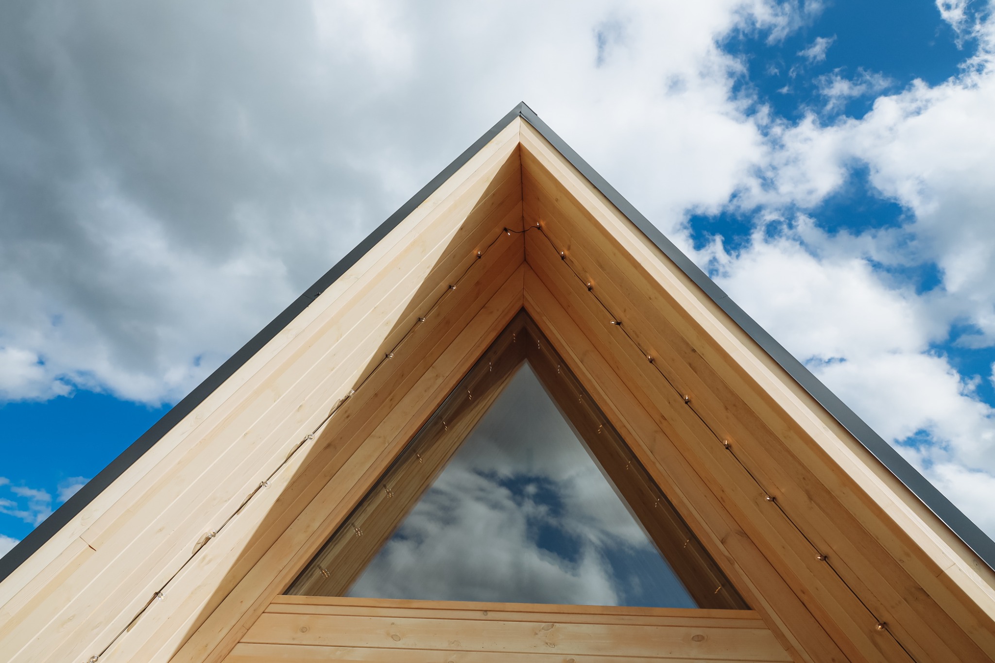 Фасад домика A-frame среди сосен